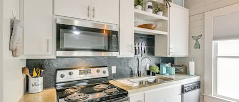 A modern kitchen with white cabinets, stainless steel appliances, and a granite countertop.
