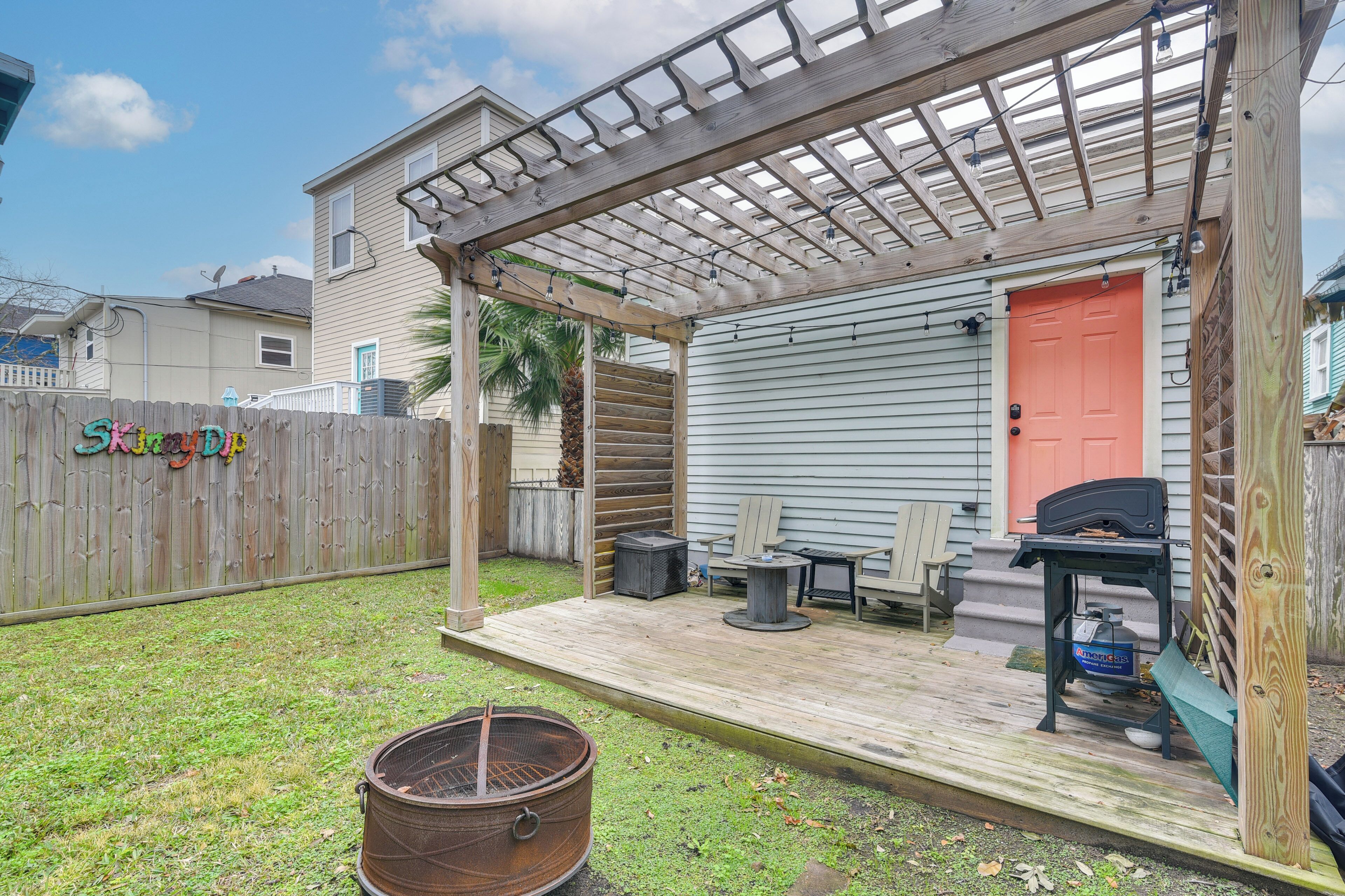 A covered patio with a grill, outdoor seating, and a wooden deck.