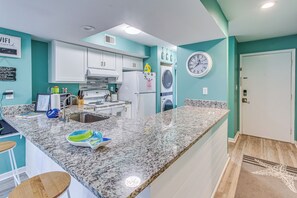 Eine Küche mit weißen Schränken, einer Granit-Arbeitsplatte, einem Spülbecken und einer Uhr an der Wand.