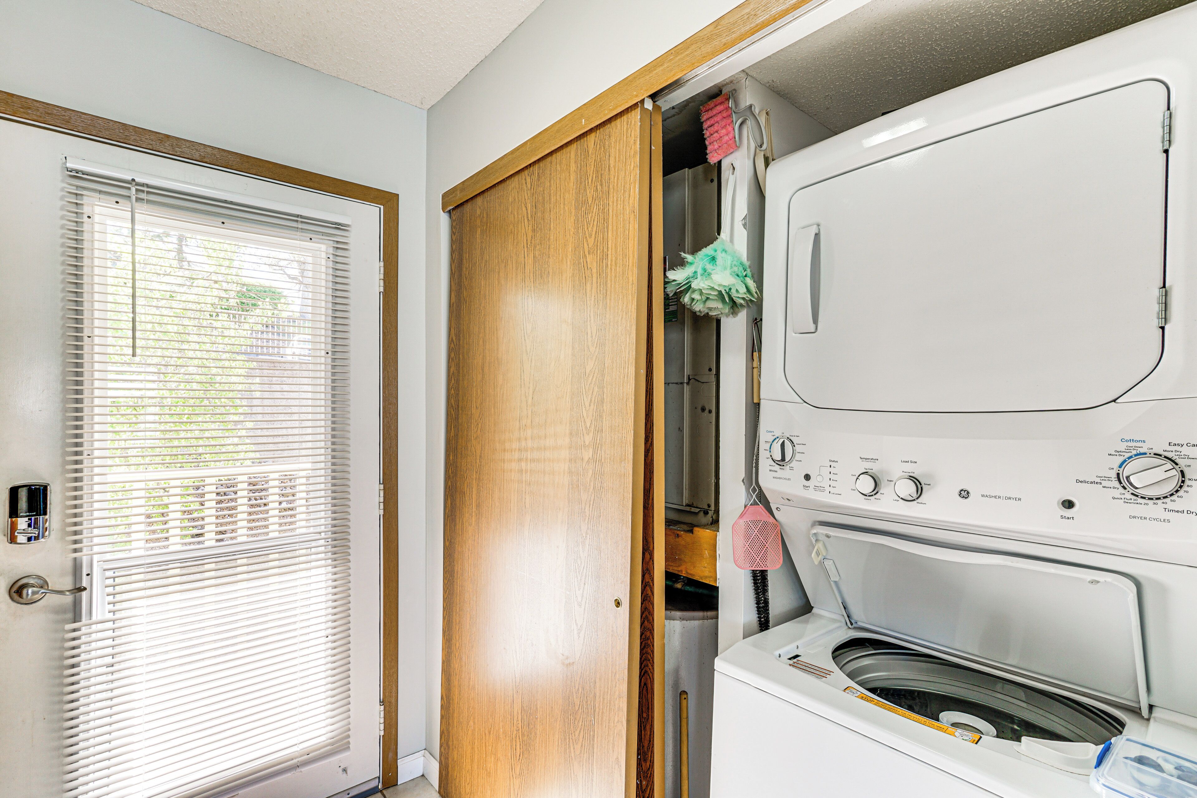A laundry room with a washing machine, a dryer, and a wooden door.