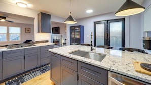 Una cocina moderna con armarios oscuros, encimeras de granito e iluminación colgante.