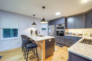 A modern kitchen with a central island, bar stools, a refrigerator, oven, and a sink. - Steps to Dtwn & Fabulous Restaurants: Chic Condo (Blowing Rock)