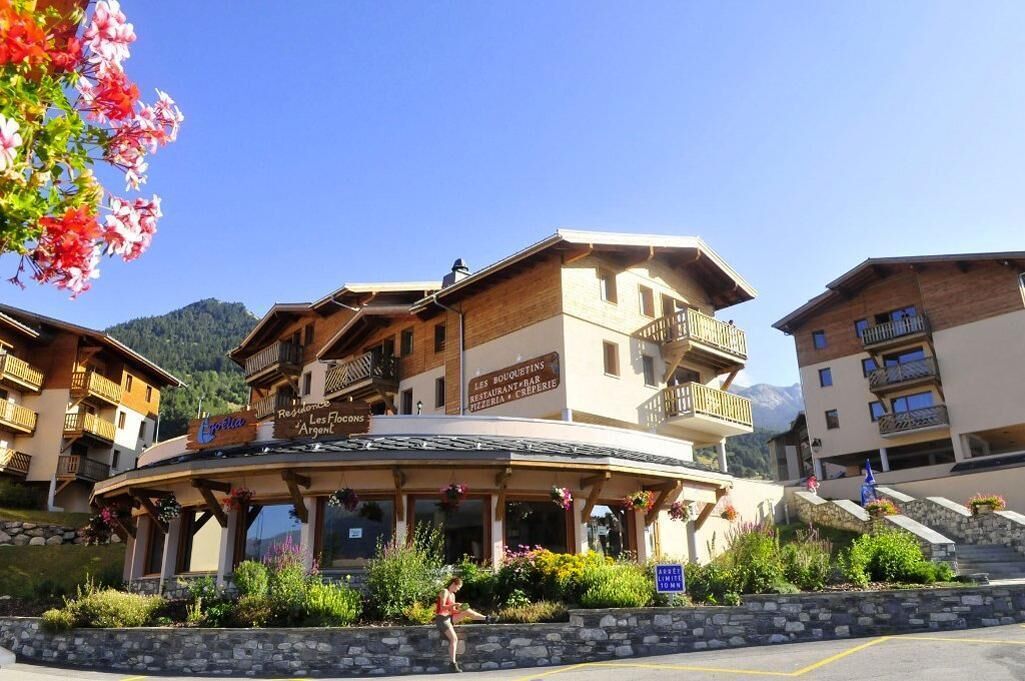 A building with a sign reading "Les Bouquins Restaurant & Bar," featuring a balcony and a stone facade.