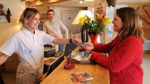 Un comptoir d’accueil en bois, un téléphone et un vase avec des fleurs.