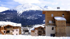 Un village de montagne enneigé, avec des bâtiments en bois et une vue dégagée sur les montagnes.
