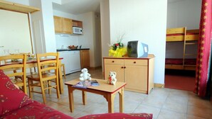 Un espace de vie compact comprenant un coin repas, une kitchenette et un lit superposé.