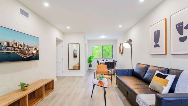 A modern living room with a cityscape painting, a sofa, a dining table, and a coffee table. - Prime Miami Location | Free Parking (Miami)