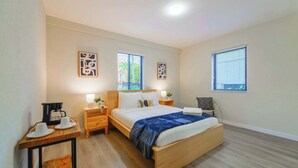 A hotel room with a bed, bedside tables, a coffee maker, and two windows. - Prime Miami Location | Free Parking (Miami)
