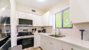 A compact kitchen with white cabinets, a microwave, a stove, and a sink. - Prime Miami Location | Free Parking (Miami)