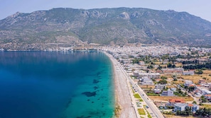 An aerial view of a coastal city with a clear blue sea, a long beachfront, and a mountainous backdrop. - Loutraki Getaway - Cozy and Quiet Nest (Loutraki-Agioi Theodoroi)