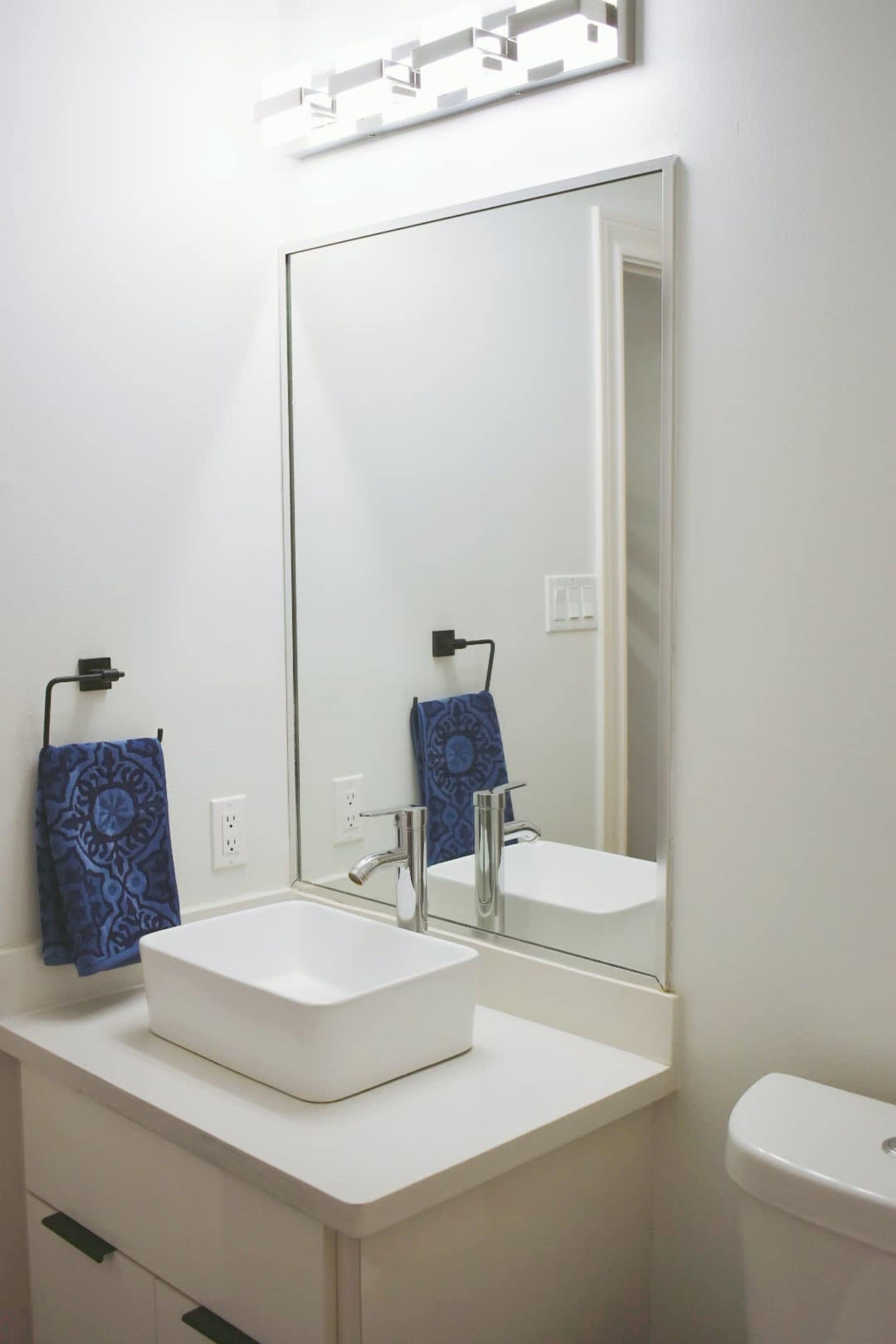 Ein Badezimmer mit einem weißen Waschbecken, einem großen Spiegel und einer Toilette.