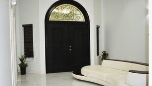 Un interior moderno con una puerta negra, un sofá blanco curvo y una planta en maceta.