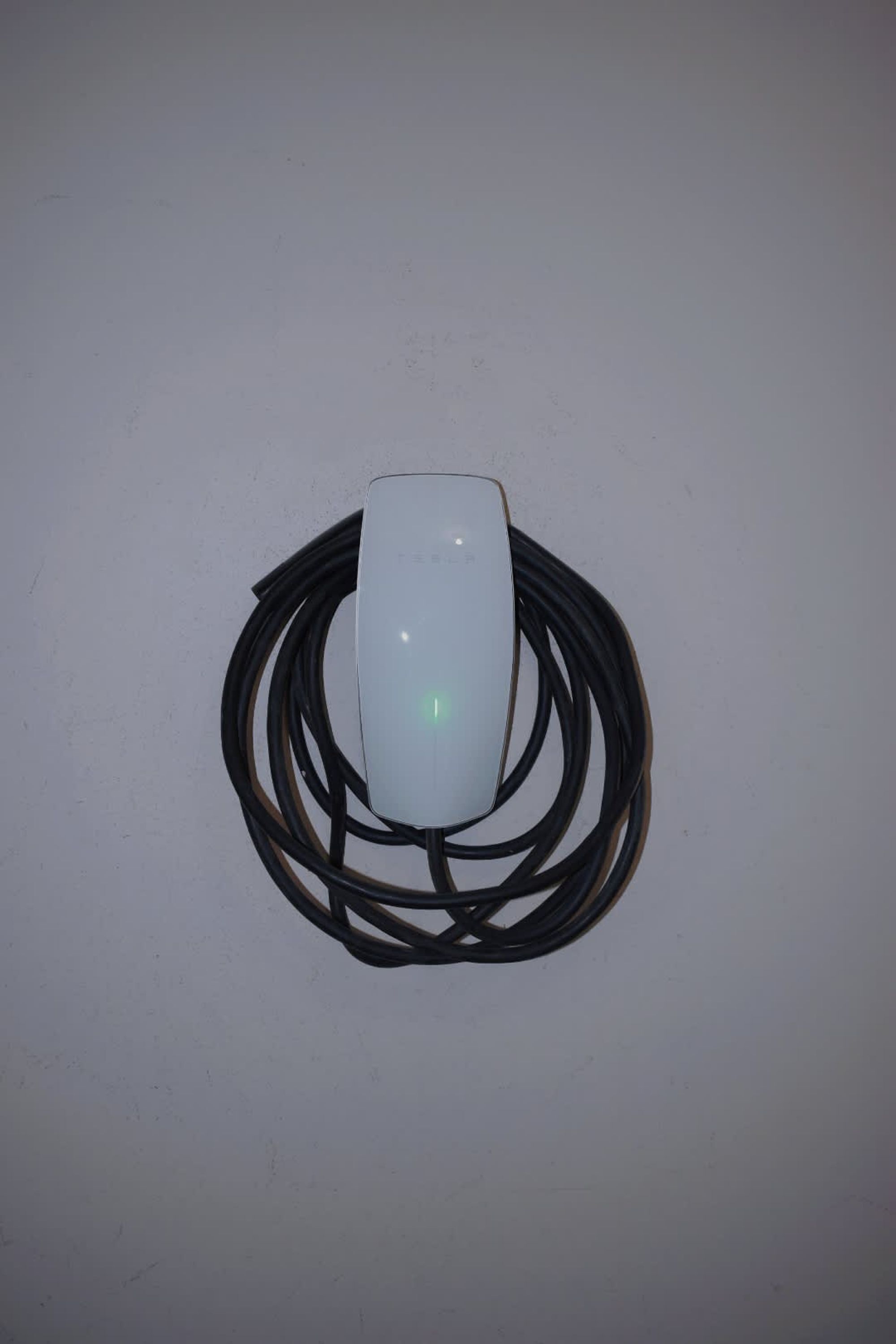 A white electrical device with a coiled cable on a plain surface.