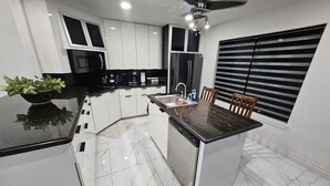 Una cocina moderna con armarios blancos, encimera de granito, lavavajillas integrado y ventilador de techo.