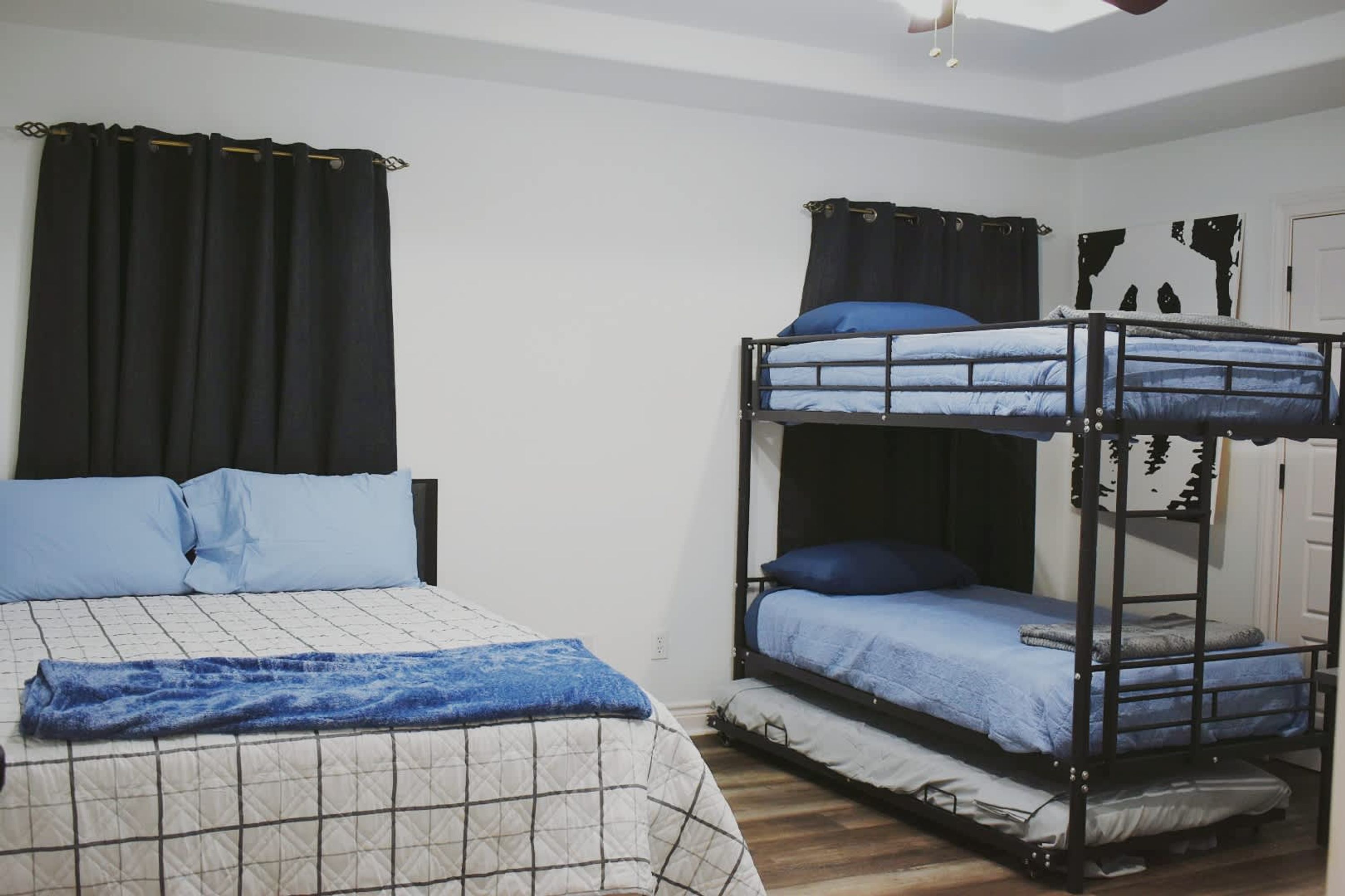 Una habitación con una cama individual, una litera y una ventana con cortinas.