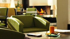 A cozy living area with green upholstered chairs, a table with a candle, and a fireplace in the background. - Fitness, swimming pool, parking, tv, 30-35m², Font Romeu (Font-Romeu-Odeillo-Via)