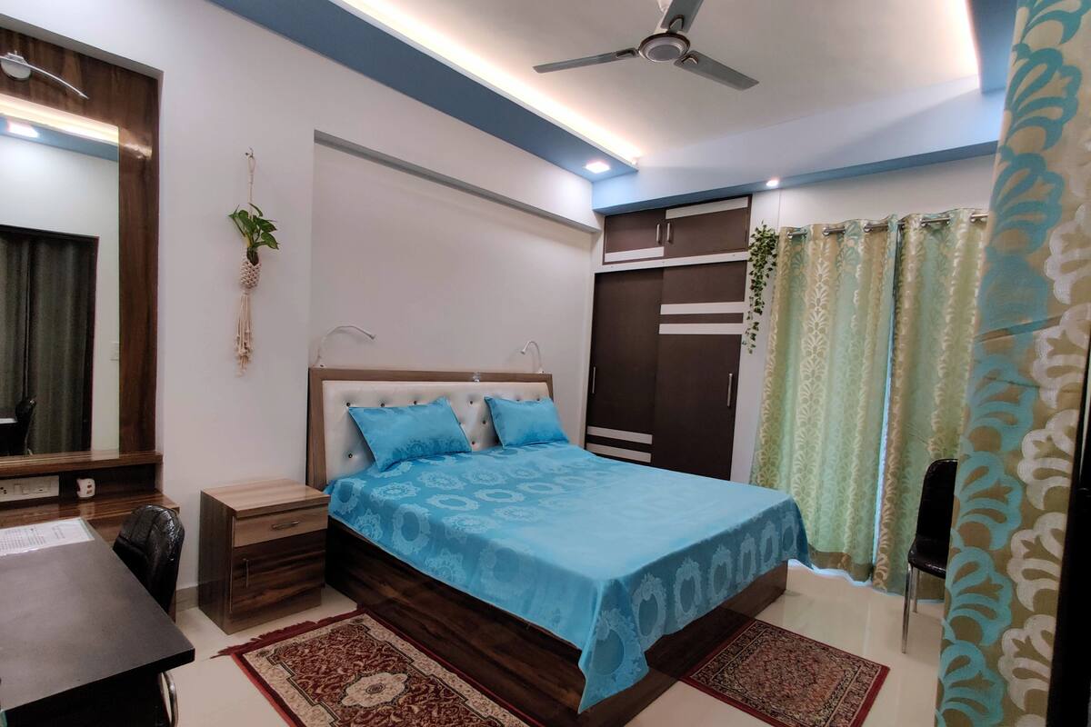 A bedroom with a bed, nightstands, a desk, a wardrobe, and a ceiling fan.