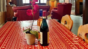 A wooden interior with a dining table set for two, a red patterned tablecloth, and two bottles of wine. - Chalet Gallois, your perfect winter escape very close to the slopes! (Nendaz)