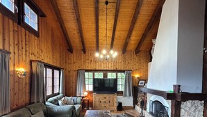 A cozy living room with a large sectional sofa, a wooden ceiling, and a fireplace. - Chalet Gallois, your perfect winter escape very close to the slopes! (Nendaz)