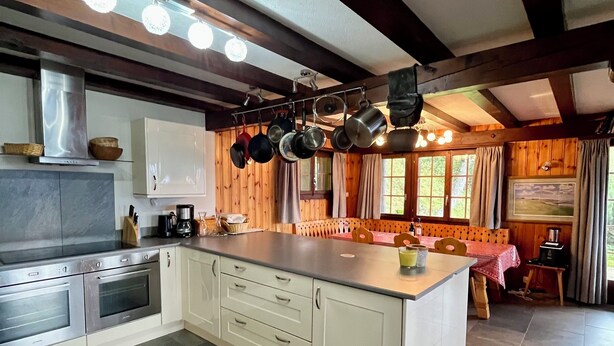 A spacious kitchen with a large island, stainless steel appliances, and hanging pots. - Chalet Gallois, your perfect winter escape very close to the slopes! (Nendaz)