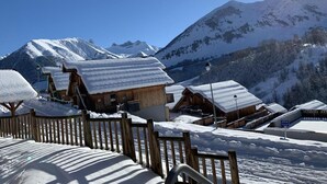 Un pueblo cubierto de nieve con edificios de madera, una cerca de madera y montañas al fondo.