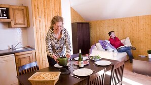 Una cocina acogedora con paredes de madera, una mesa de comedor dispuesta con platos, una botella y una cesta de pan.