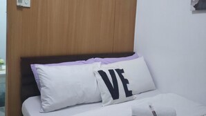 A bedroom with a wooden headboard, a bed with white bedding, and a pillow with the word "LOVE". - 5-Minutes Walk to Mall of Asia, One-bedroom with Balcony at Shell Residences (Pasay)