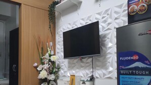A modern kitchen with a flat-screen TV, a refrigerator, and a dining area with a table and chairs. - 5-Minutes Walk to Mall of Asia, One-bedroom with Balcony at Shell Residences (Pasay)