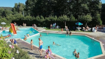 A swimming pool with multiple lanes, surrounded by greenery and trees.