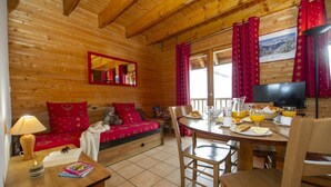 Ein gemütliches Holzhaus mit Essbereich, einer Couch mit roten Kissen und einem Fernseher.