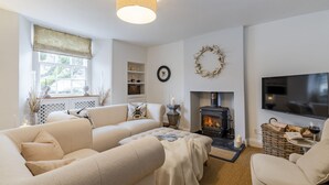 A cozy living room with a fireplace, sofas, a TV, and a bookshelf. - Antelope Cottage - Northleach, Cotswolds - near pubs (Northleach)