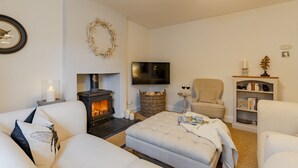 A cozy living room with a fireplace, a comfortable sofa, a television, and a bookshelf. - Antelope Cottage - Northleach, Cotswolds - near pubs (Northleach)