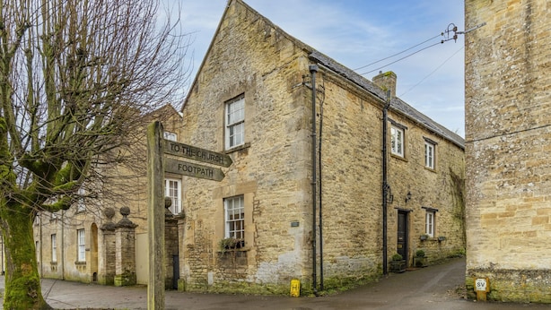 A stone building with a sign indicating a church and footpath. - Antelope Cottage - Northleach, Cotswolds - near pubs (Northleach)