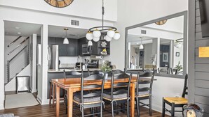 A modern kitchen with a wooden dining table and chairs, a built-in oven, and a large mirror above the counter. - Apres Chalet: Winterplace Ski-in/Out pool+hot tubs (Ludlow)