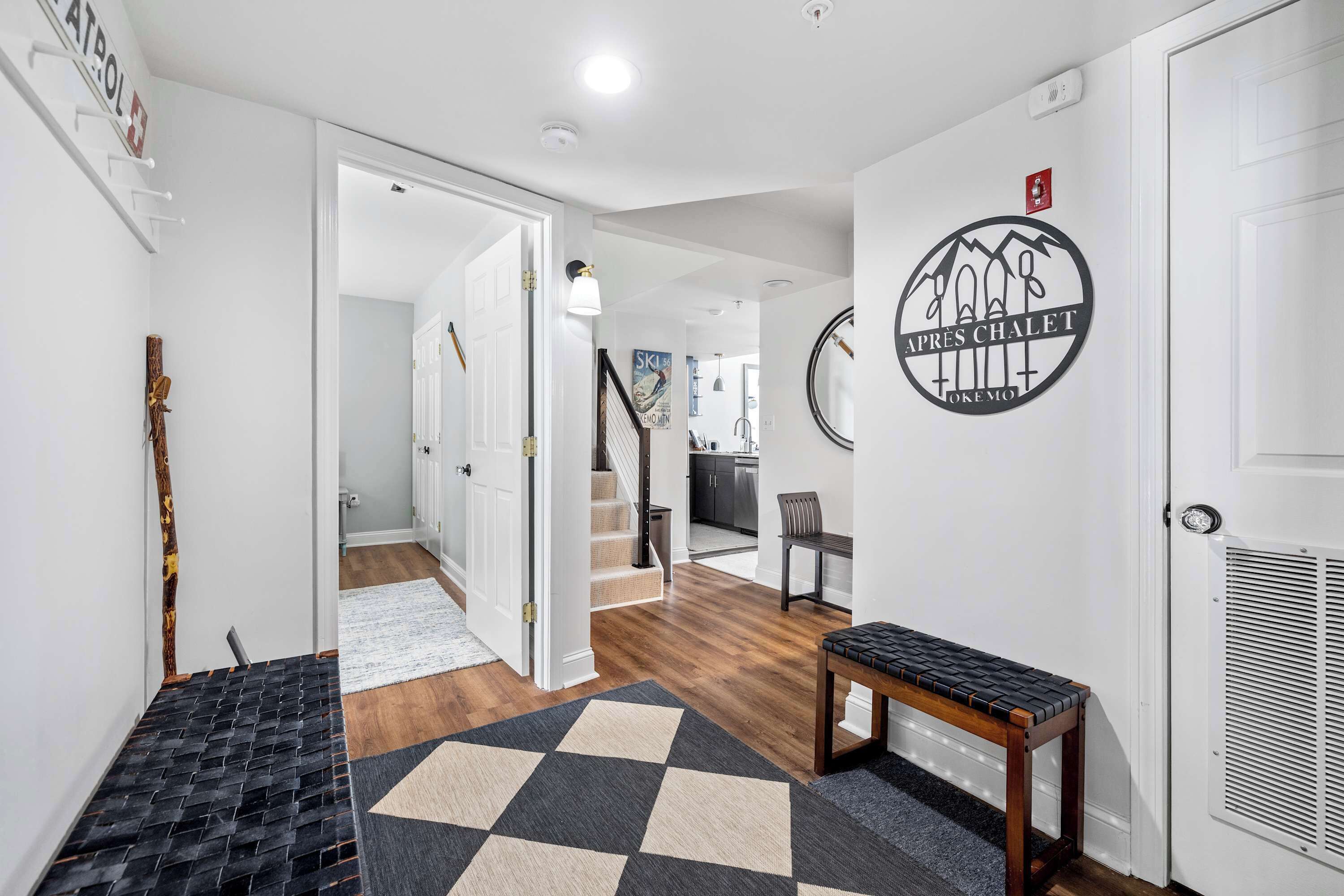 Un couloir avec un tapis à carreaux, un banc et un mur orné d’un logo.
