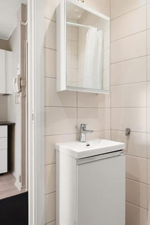 Ein Badezimmer mit weißem Waschbecken, einem Spiegel und einer Duschvorhang.