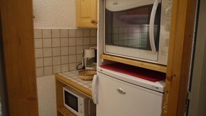 A compact kitchen with a microwave, toaster, and coffee maker on a tiled backsplash. - 70m from ski slopes, 3rd floor, view ski slopes, balcony, tv, 27m², Méribel-Mottaret (Méribel - Les Allues)