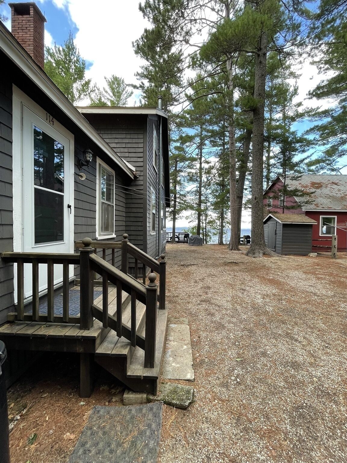 A residential property with a wooden deck, a front porch, and a gravel driveway.