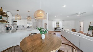 A modern kitchen with white cabinetry, a central island, and pendant lighting. - Coastal Cottage 2 Bedroom Home (Sarasota)
