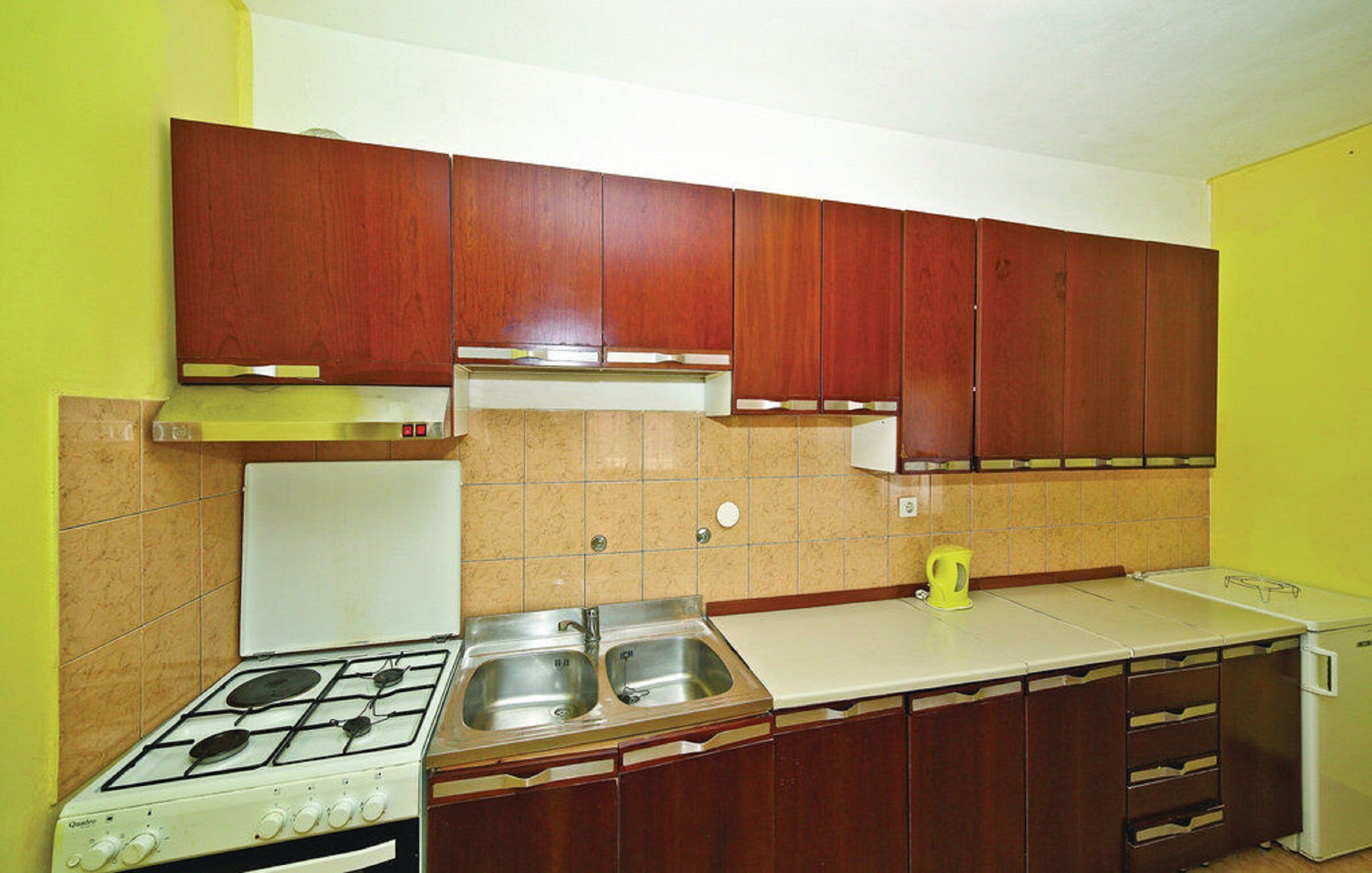 A kitchen with wooden cabinets, a gas stove, a sink, and a white refrigerator.