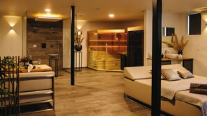 A modern living room with a sofa, a dining table set with wine, and a kitchen area with a sink and cabinets. - Waal Wellness Villa Maas and Waal Wellness & Suites (Dreumel)