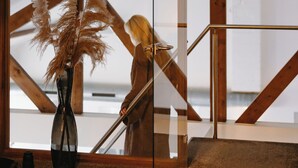 A room with a glass door, wooden beams, and a tall vase with dried plants. - Waal Wellness Villa Maas and Waal Wellness & Suites (Dreumel)