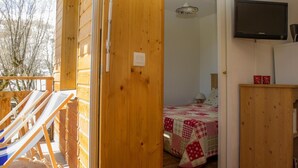 Een houten kamer met een bed, een televisie en een balkon met ligbedden.