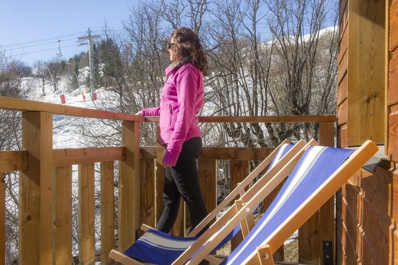 A person on a wooden deck with a blue and white striped lounge chair.