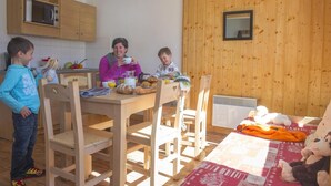 A wooden-paneled room with a dining table, chairs, and a kitchen area with a microwave. - 50m from ski slopes, swimming pool, sauna, balcony, tv, ski locker, 35-40m², Saint Sorlin d'Arves (Saint-Sorlin-d'Arves)