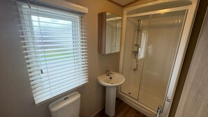 Un baño con inodoro, lavamanos y cabina de ducha de vidrio.