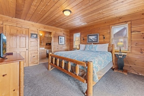 A wooden cabin bedroom with a bed, a desk, and a dresser. - Spacious Cabin for 8 w/Hot Tub & Mountain Views! (Gatlinburg)