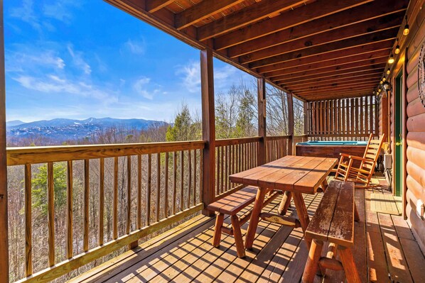 A wooden deck with tables and benches, a pool, and a view of mountains. - Spacious Cabin for 8 w/Hot Tub & Mountain Views! (Gatlinburg)