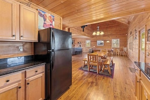 A wooden cabin interior with a kitchen, dining area, and a large window. - Spacious Cabin for 8 w/Hot Tub & Mountain Views! (Gatlinburg)