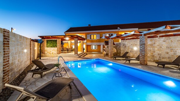 A swimming pool with lounge chairs and a covered patio area. - Villa Mendula Zadar Villas (Novigrad)